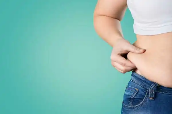 Image of woman pinching her love handles to show weight gain Alcester